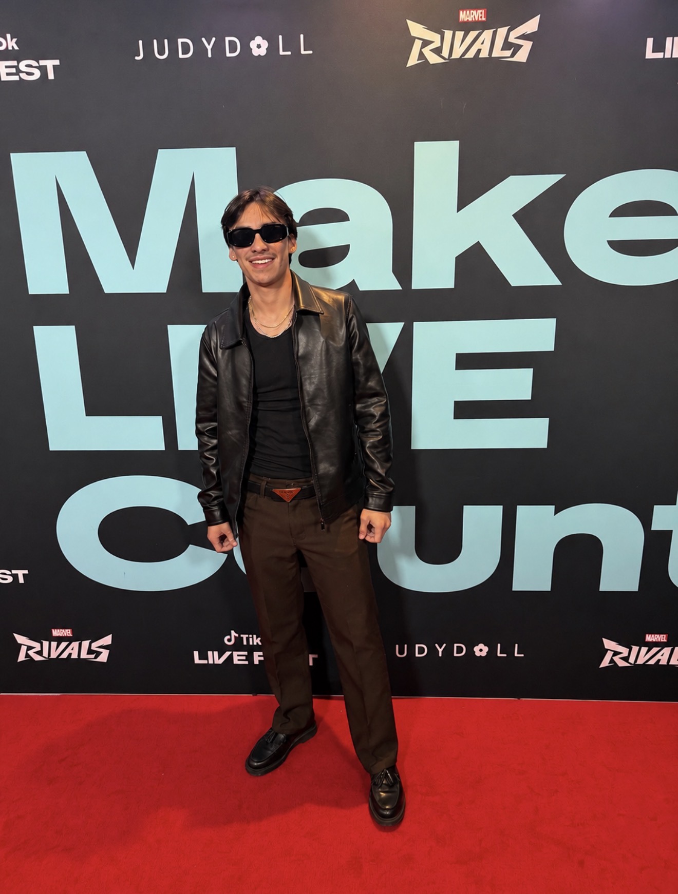 Austin de Leon wearing sunglasses and a black jacket at an event